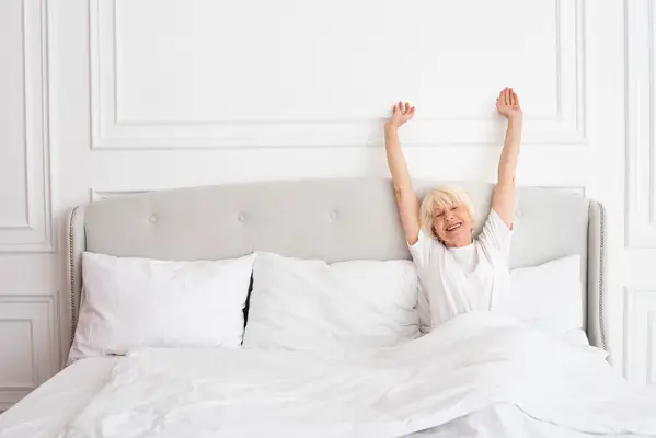 Mujer mayor feliz después de dormir en el colchón