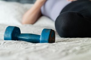 Persona tumbada en un colchón con una pesa al lado